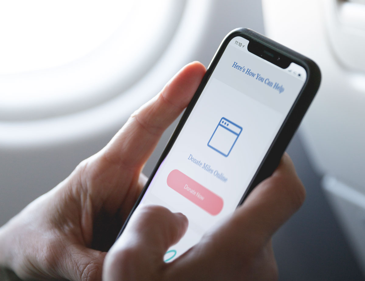 Close up mockup of hands holding iPhone with Wishes in Flight donation landing page.
